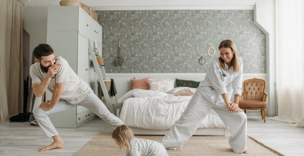 A joyful family bonding through morning stretches in a cozy bedroom setting.